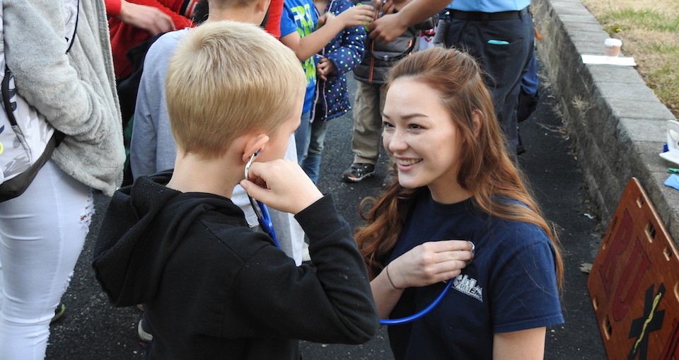 Hailey Laird, right, lets a child use a stethoscope to hear her heart beat.